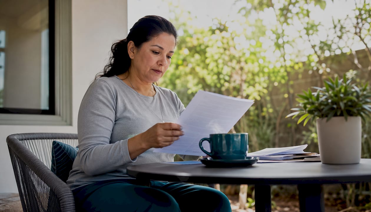 Una mujer revisa papeles de trámites de extranjería desde su oficina en casa.