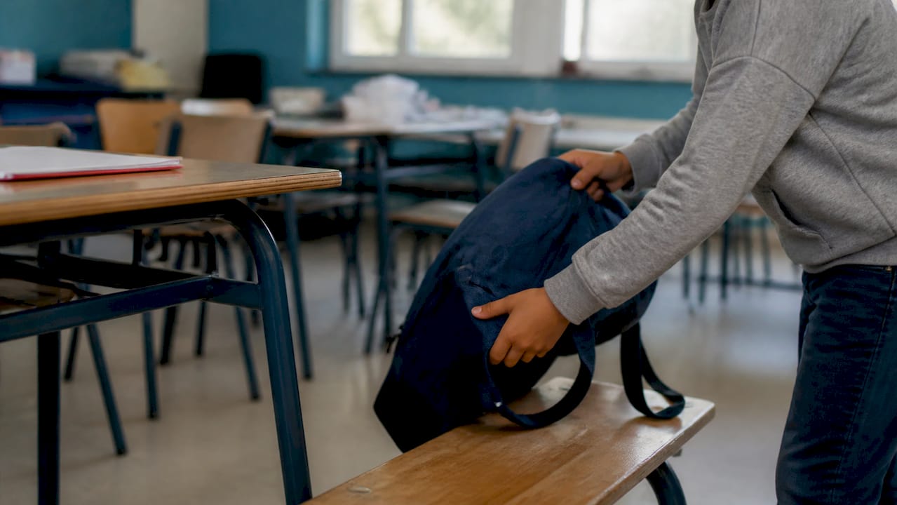 Un niño deja su mochila en el aula antes de empezar las clases.