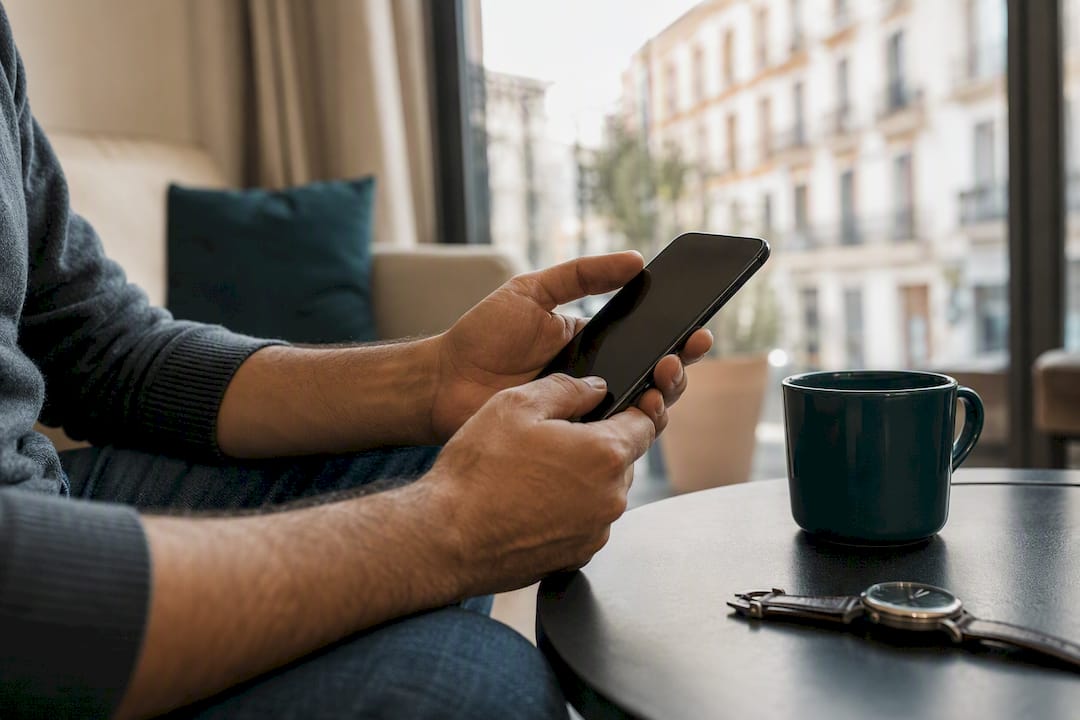 Manos con móvil apagado firmando digitalmente desde casa